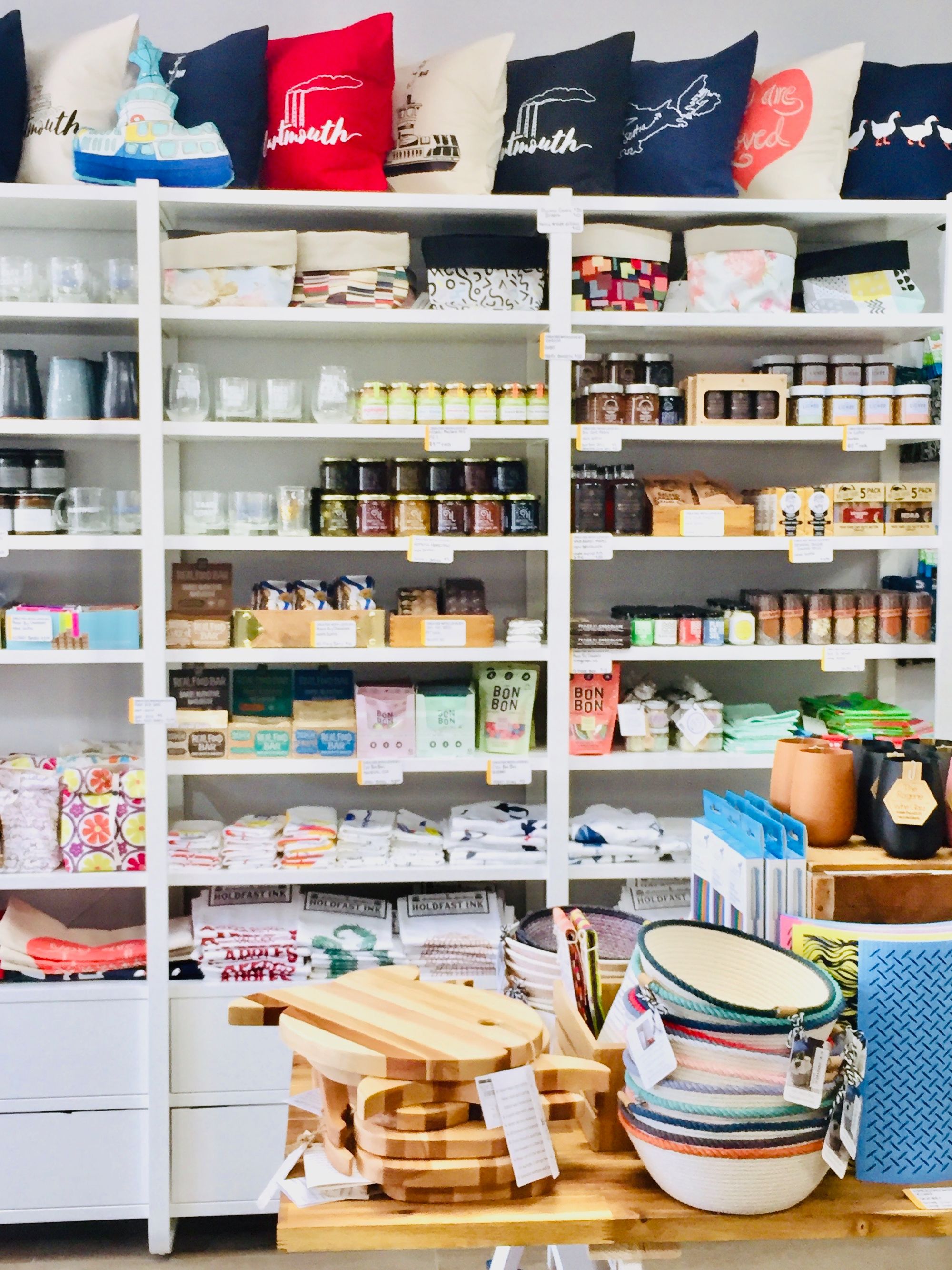 The interior of The Trainyard store in Dartmouth, Nova Scotia. In front of shelves displaying handmade goods is a table piled