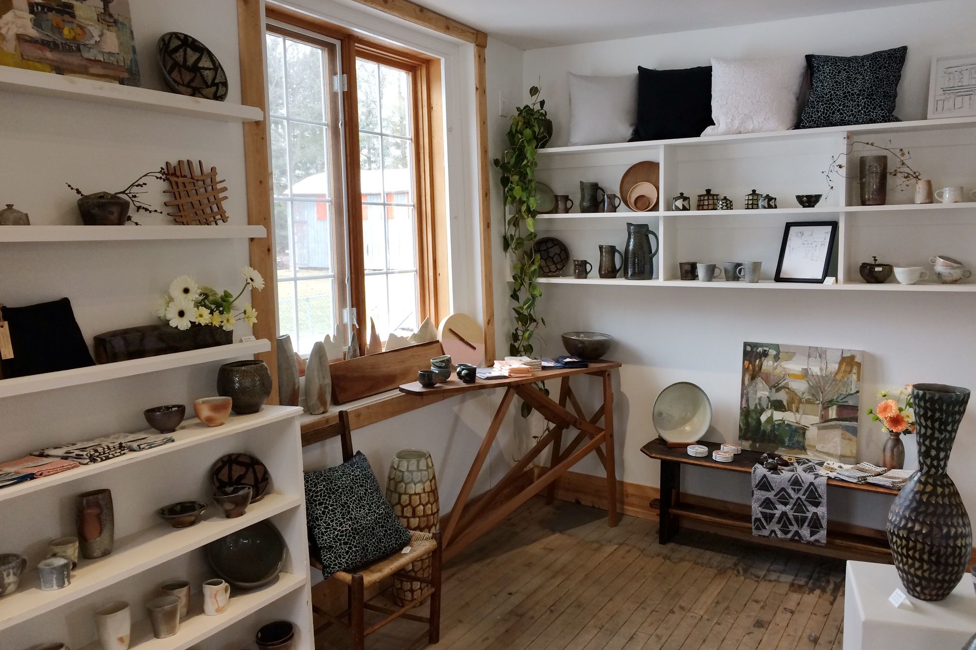 The interior of the Black & Smith shop filled with displays of handmade jugs, bowls, vases and pillows on shelves.