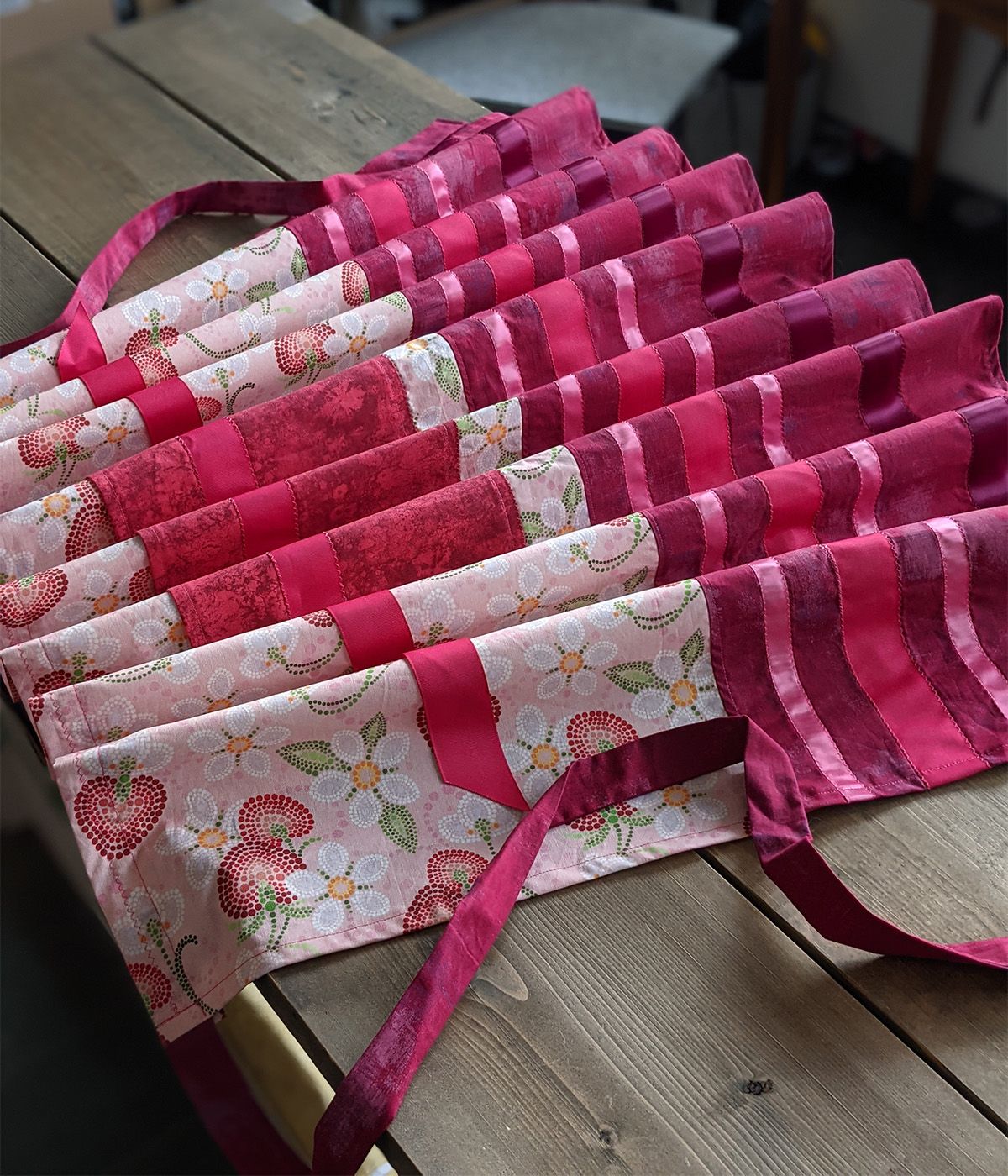 A ribbon apron made with Indigenous Nouveau strawberry fabric, on a wooden table