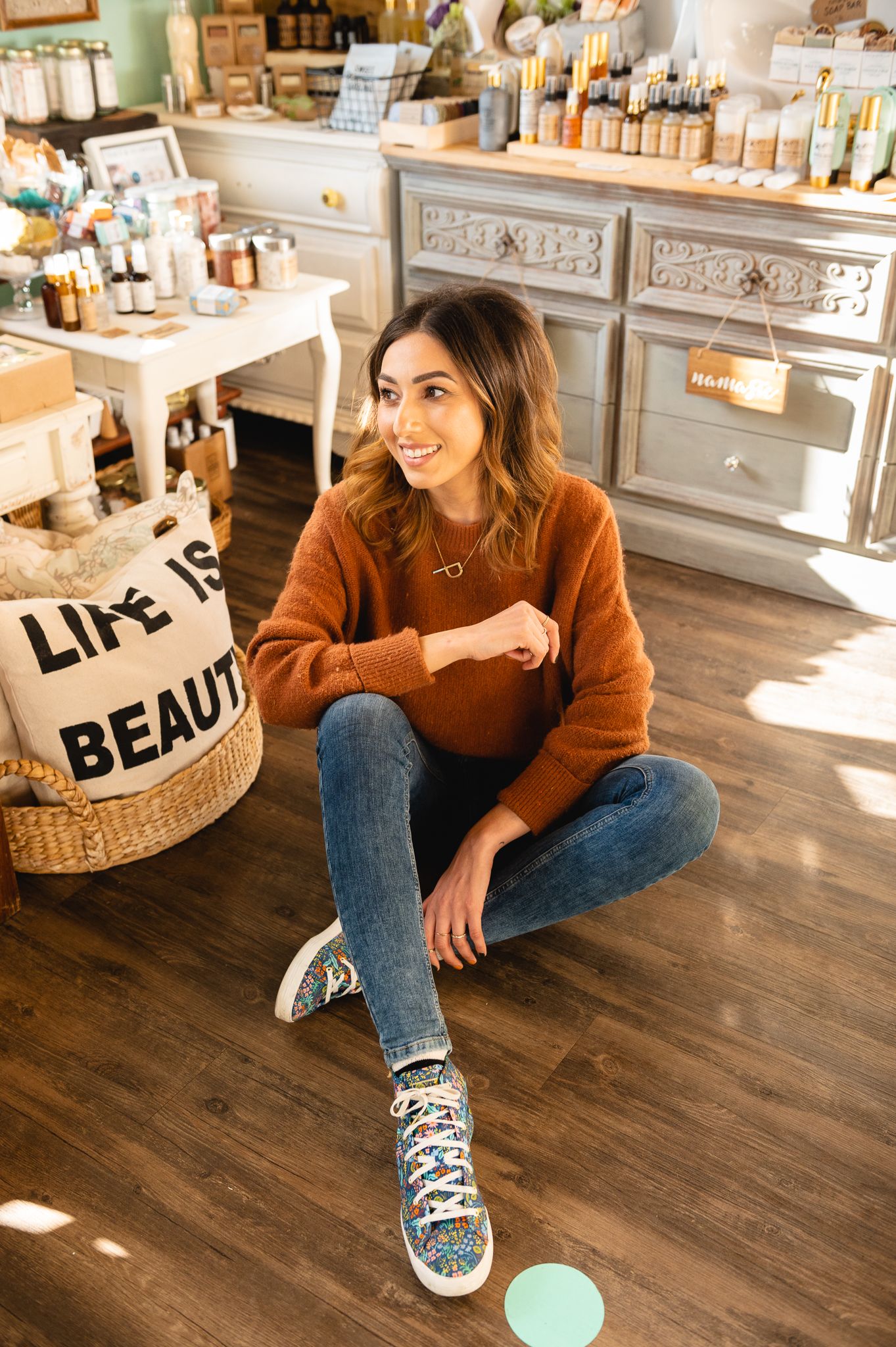 Shop owner Piya Sandhu sits in front of a display of bath-and-body products.
