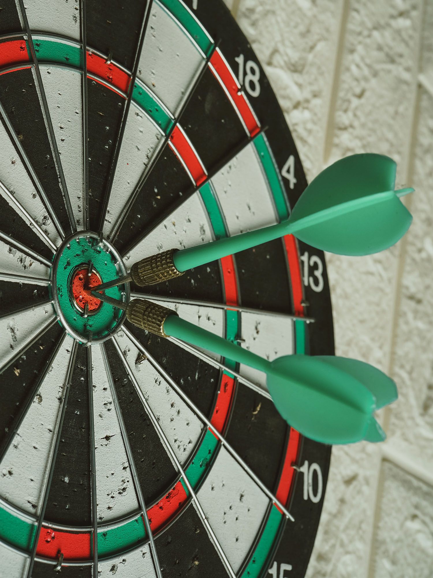 A well-used dart board with two darts in the bull's eye