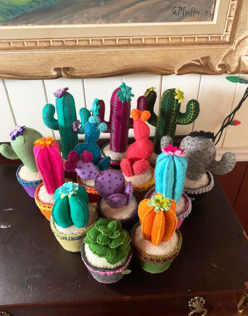 A group of colourful succulents and cacti made out of wool felt, on a table