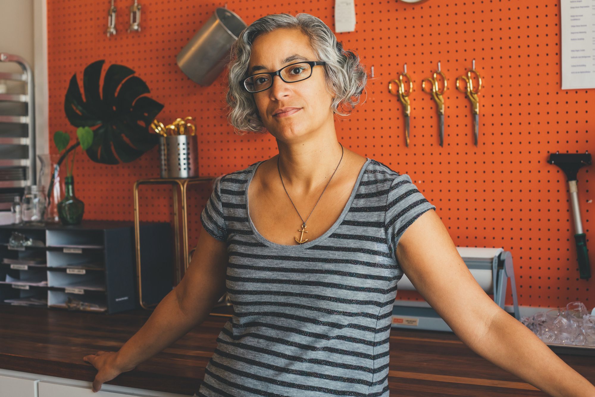 A woman, Arianne Foulks, stands in front of a work desk.