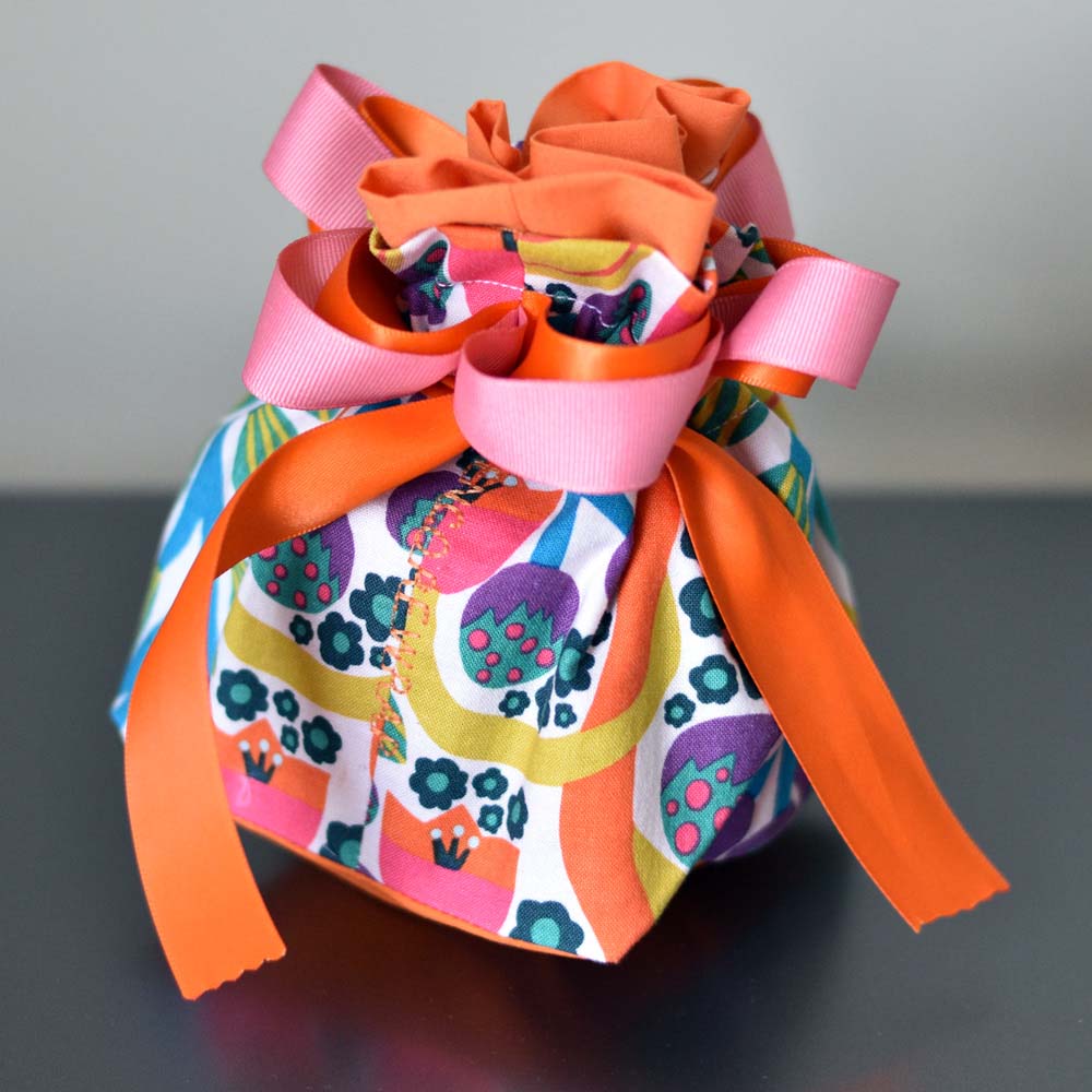 A colourful reusable gift bag with ribbons and a bow