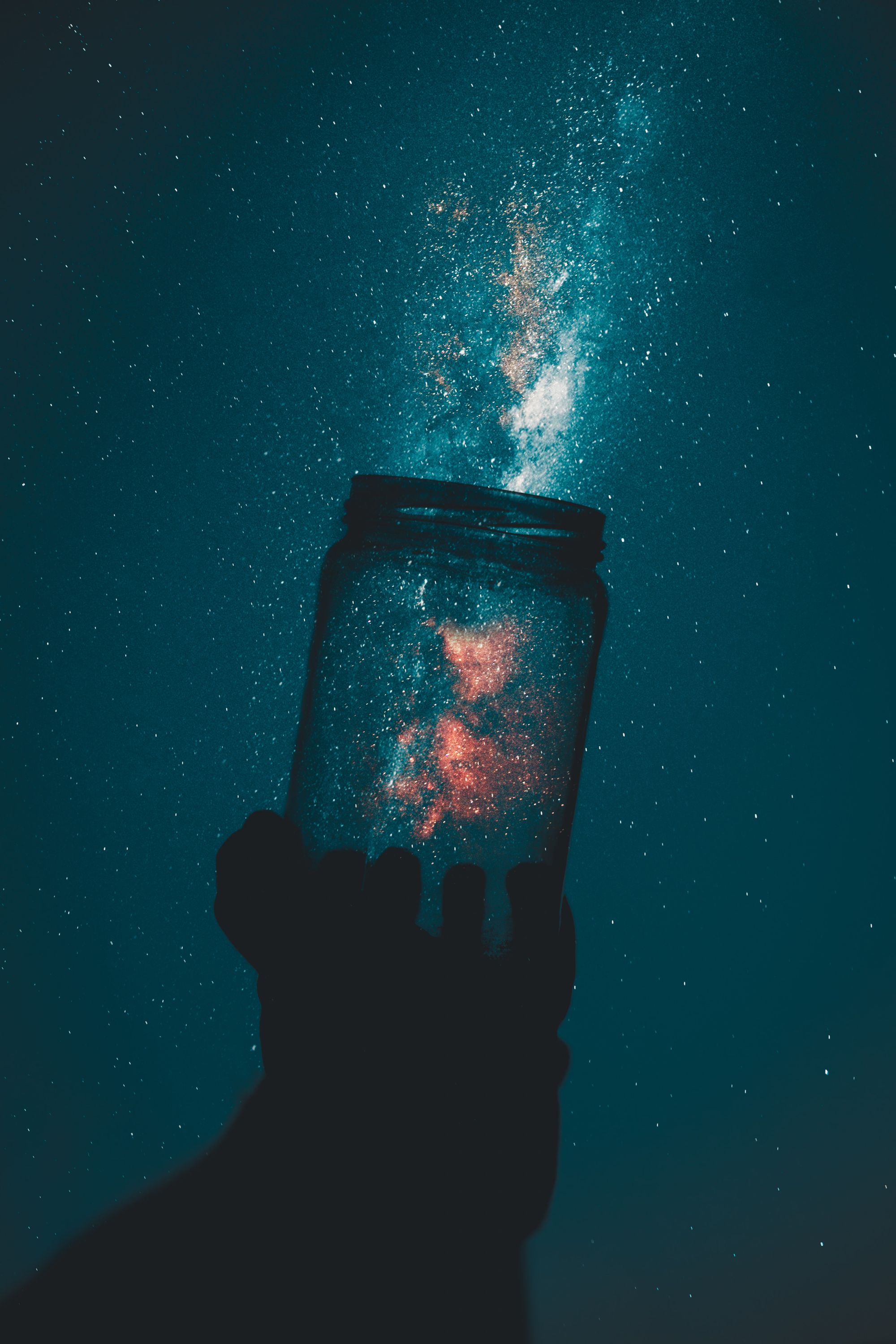 A glass jar looks to be capturing or releasing a galaxy of stars