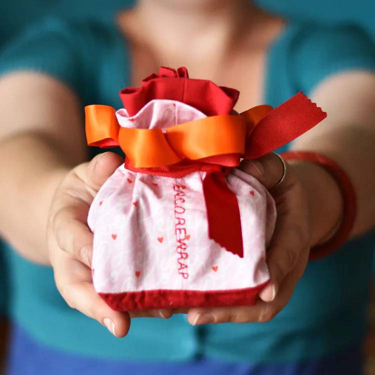person holding out package wrapped in fabric gift wrap