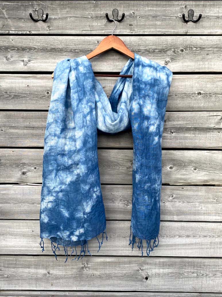 indigo-dyed shawl with tassels hanging against wooden wall