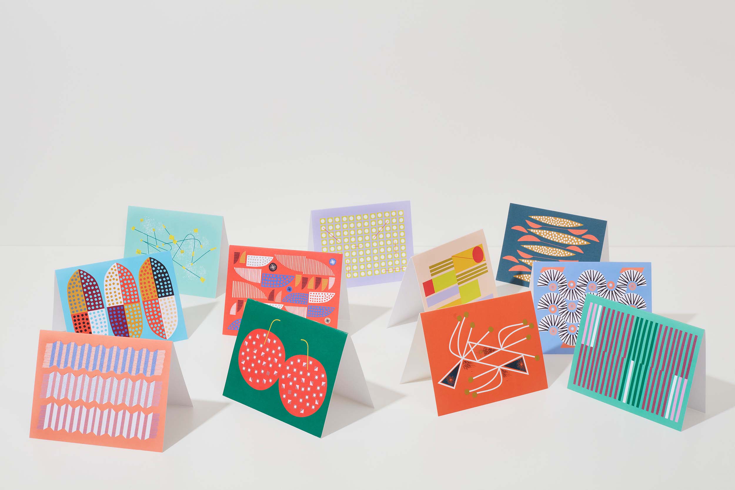 A group of colourful, graphic greeting cards on a table, by Mezzaluna Studio