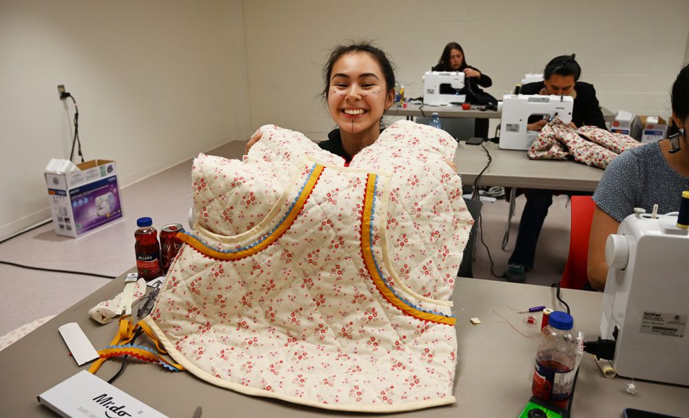 A person smiling holding up a quilted garment