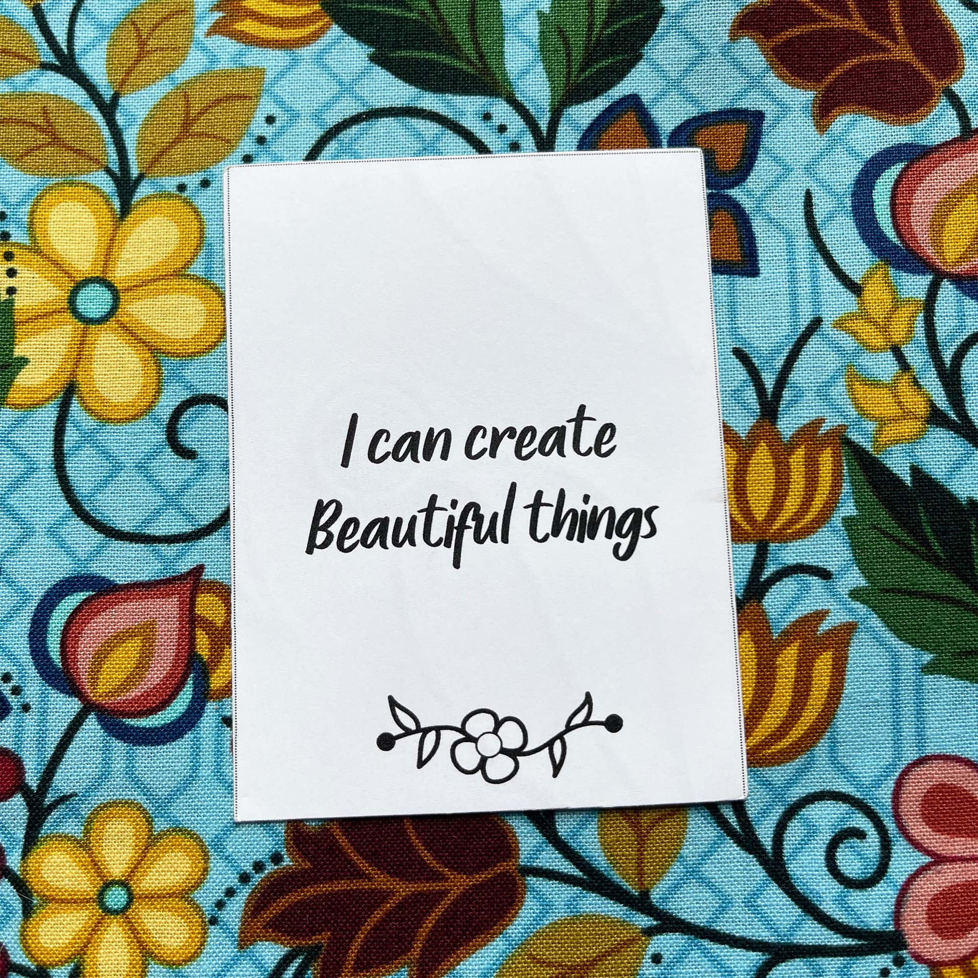 A card stating "I can create beautiful things" on a floral fabric background